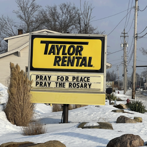 A yellow sign in a snowy landscape reads 