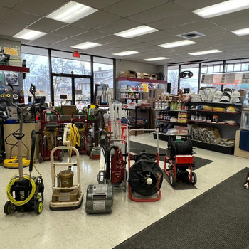 Store interior featuring cleaning equipment like vacuums and scrubbers lined up in the center. Shelves hold various supplies, creating a tidy, organized atmosphere.